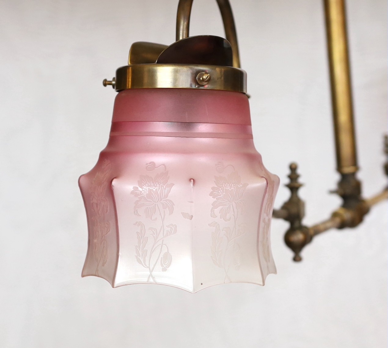 A late 19th century brass gasolier twin branch ceiling light with cranberry tinted etched glass shades, height 43cm. extends to 95cm